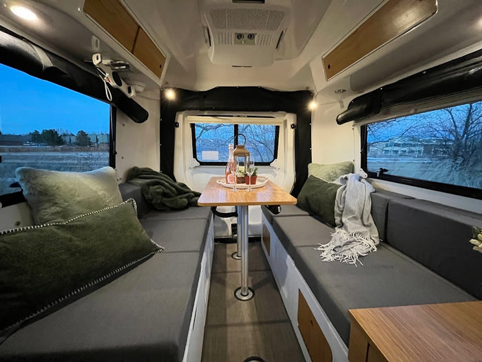 with an evening outdoor view.|This inviting rv rental interior features a grey sofa with green pillows