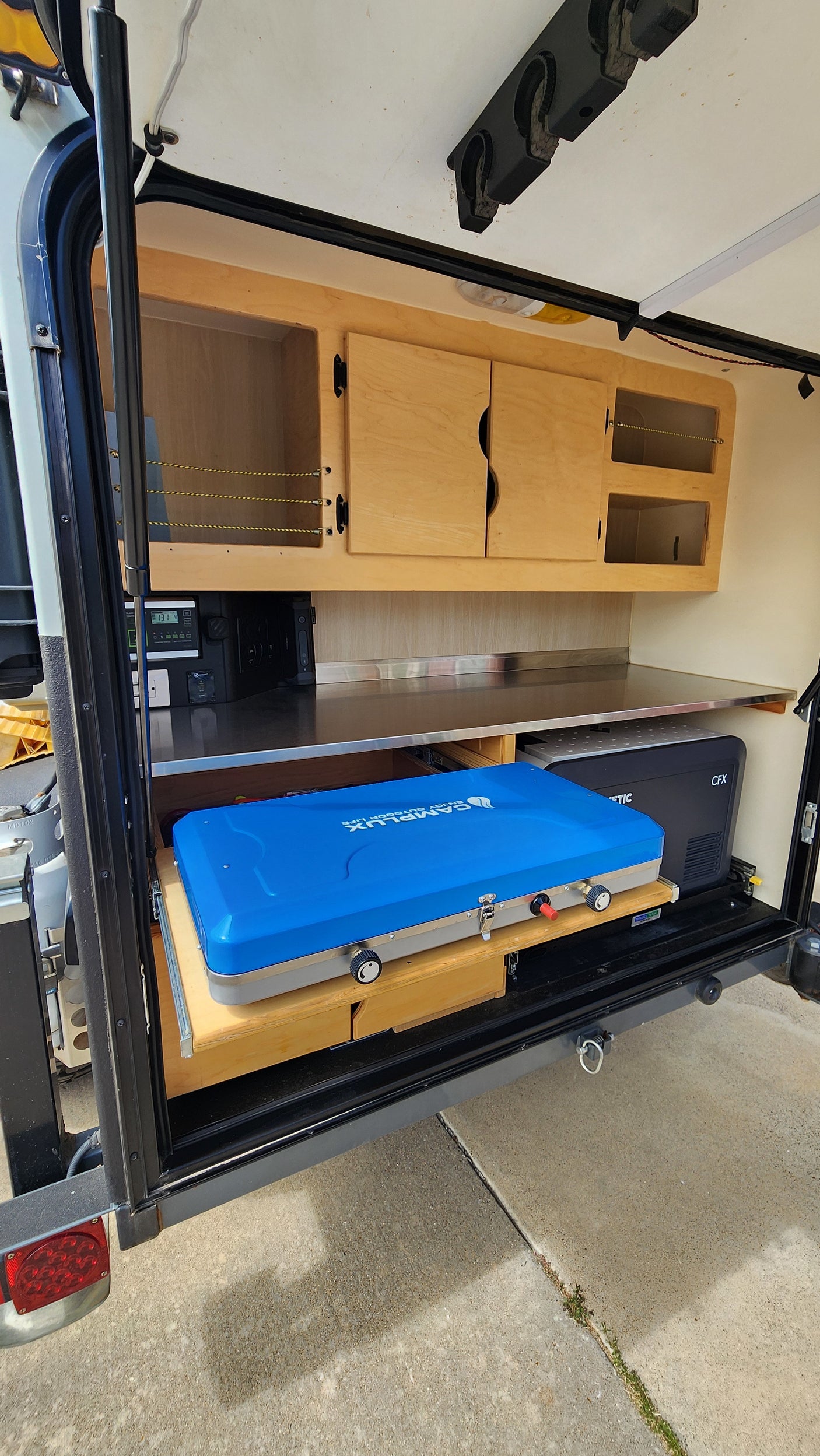 This compact RV rental features an outdoor kitchen with a CampLux stove, Dometic fridge, and ample storage for camping.