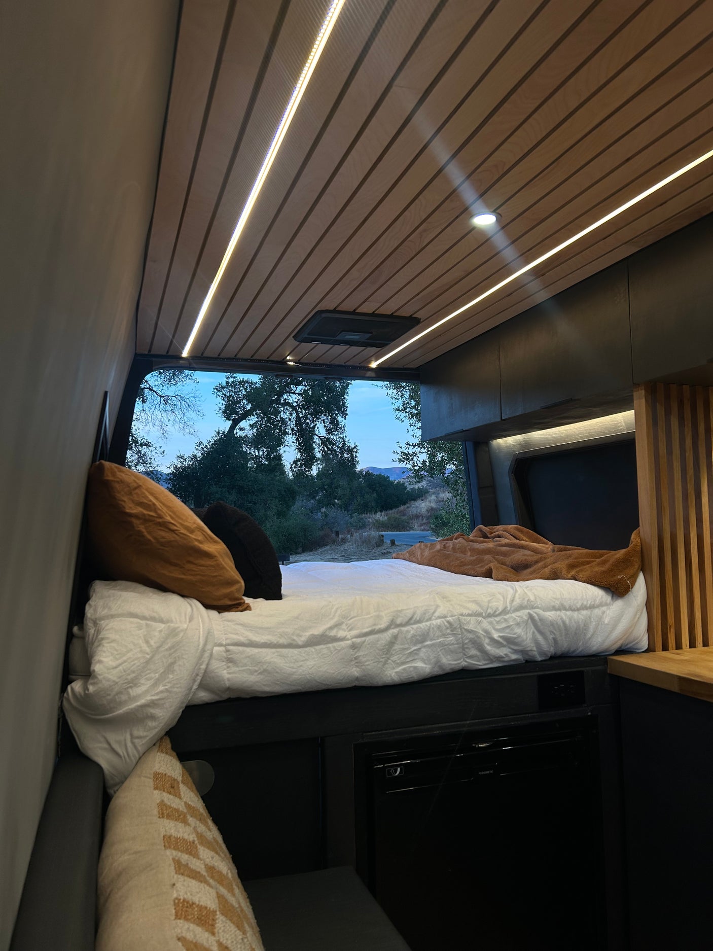 Cozy RV rental interior with bed & ambient lighting, perfect for van life adventures with a view.