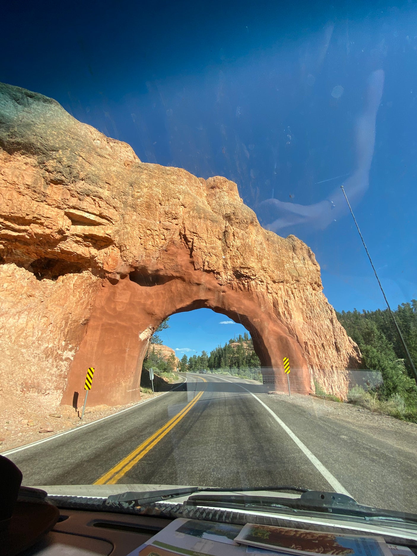 Driving an RV rental through a stunning red rock tunnel under a bright blue sky.