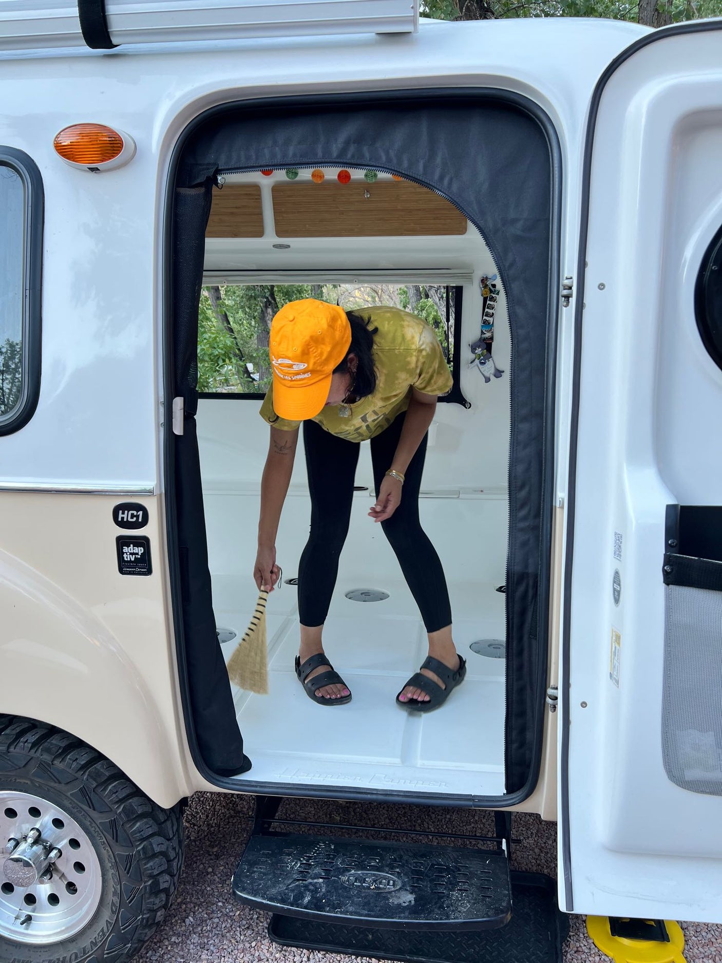 Daily chores in an RV rental. A person sweeps the camper's tidy interior, ready for more mobile living adventures.