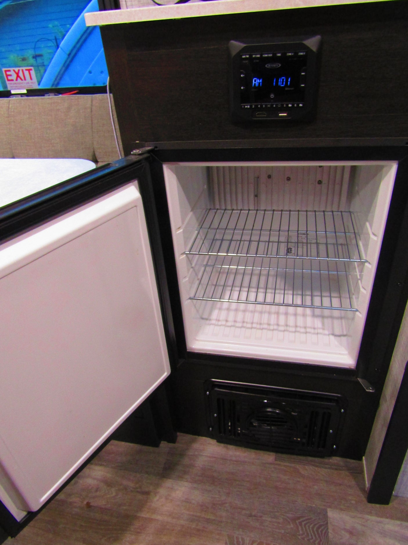 Explore your rv rental's interior: an open built-in mini-fridge with shelves, and a control panel displaying AM 11:01.