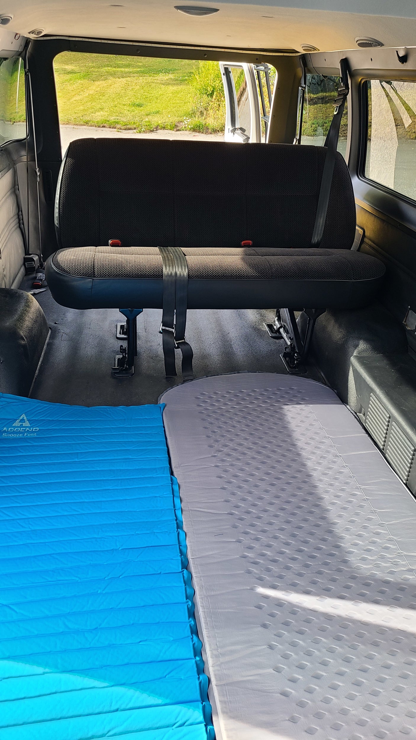 RV rental interior featuring a bench seat & two laid-out sleeping pads, ideal for comfortable van camping.