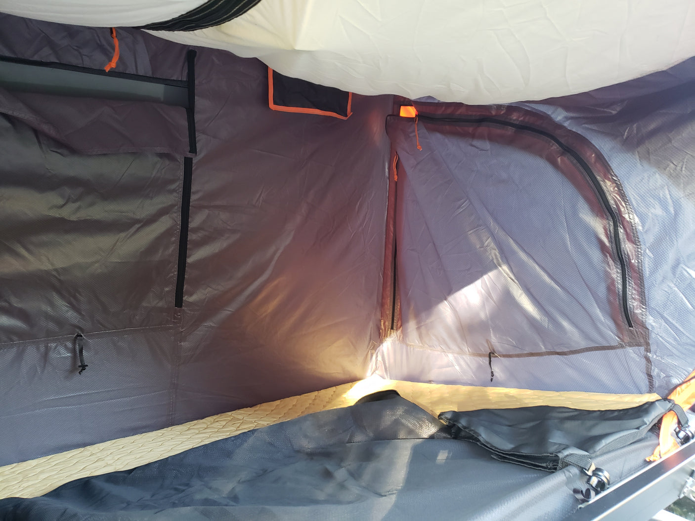 Inside a cozy RV rental tent: a comfortable sleeping area with light filtering through the mesh window.