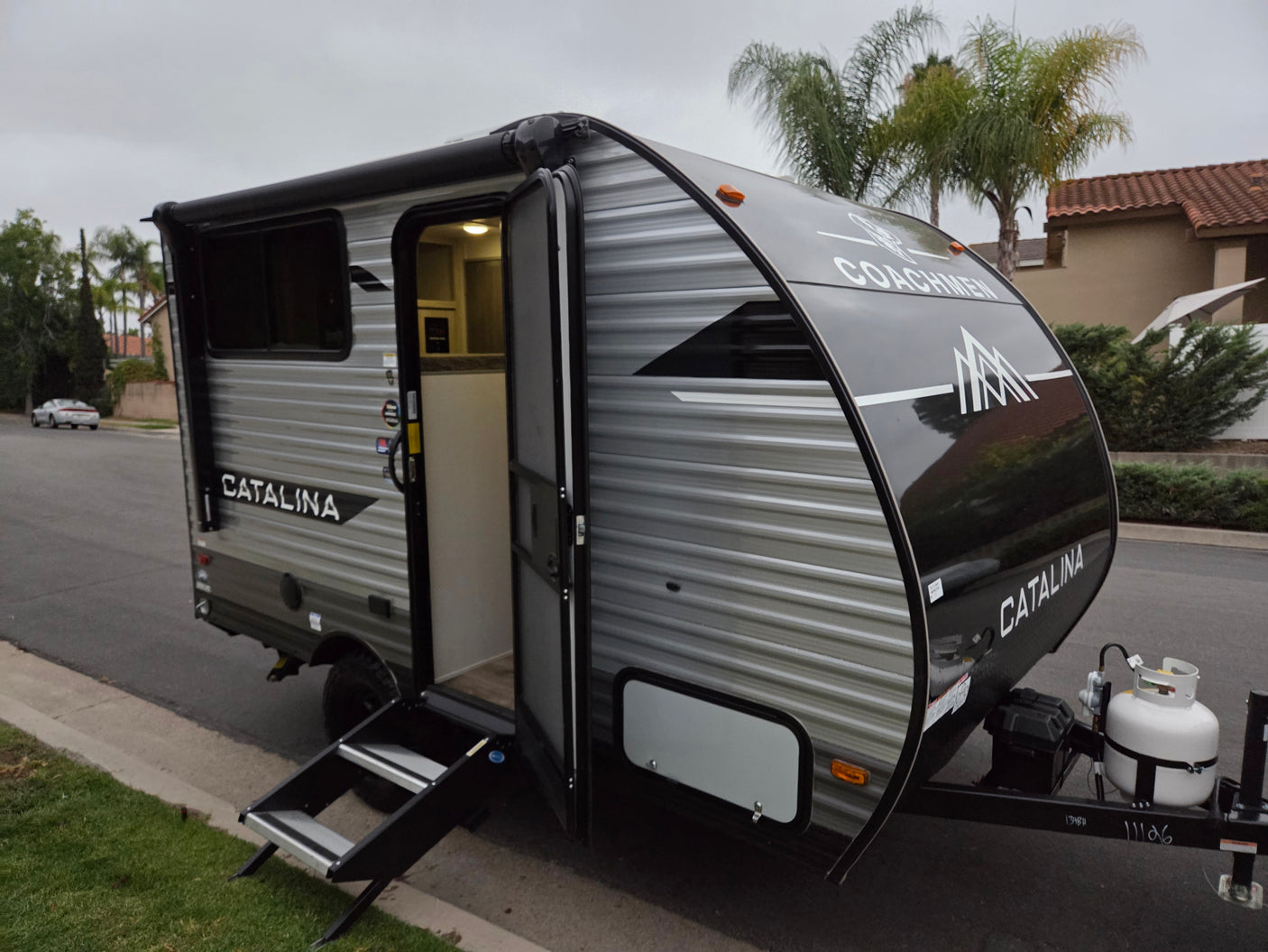 This Coachmen Catalina RV rental is a sleek silver and black travel trailer, door open with steps down, ready for your next adventure.