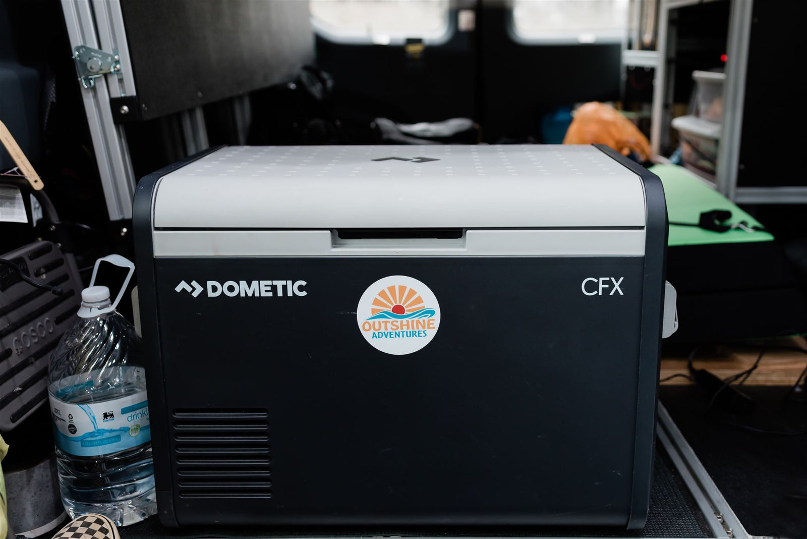 a comfy bed with patterned linens holds pillows reading 'SHINE ON' and 'Life is a beautiful ride.'|Cozy and functional camper van bed setup