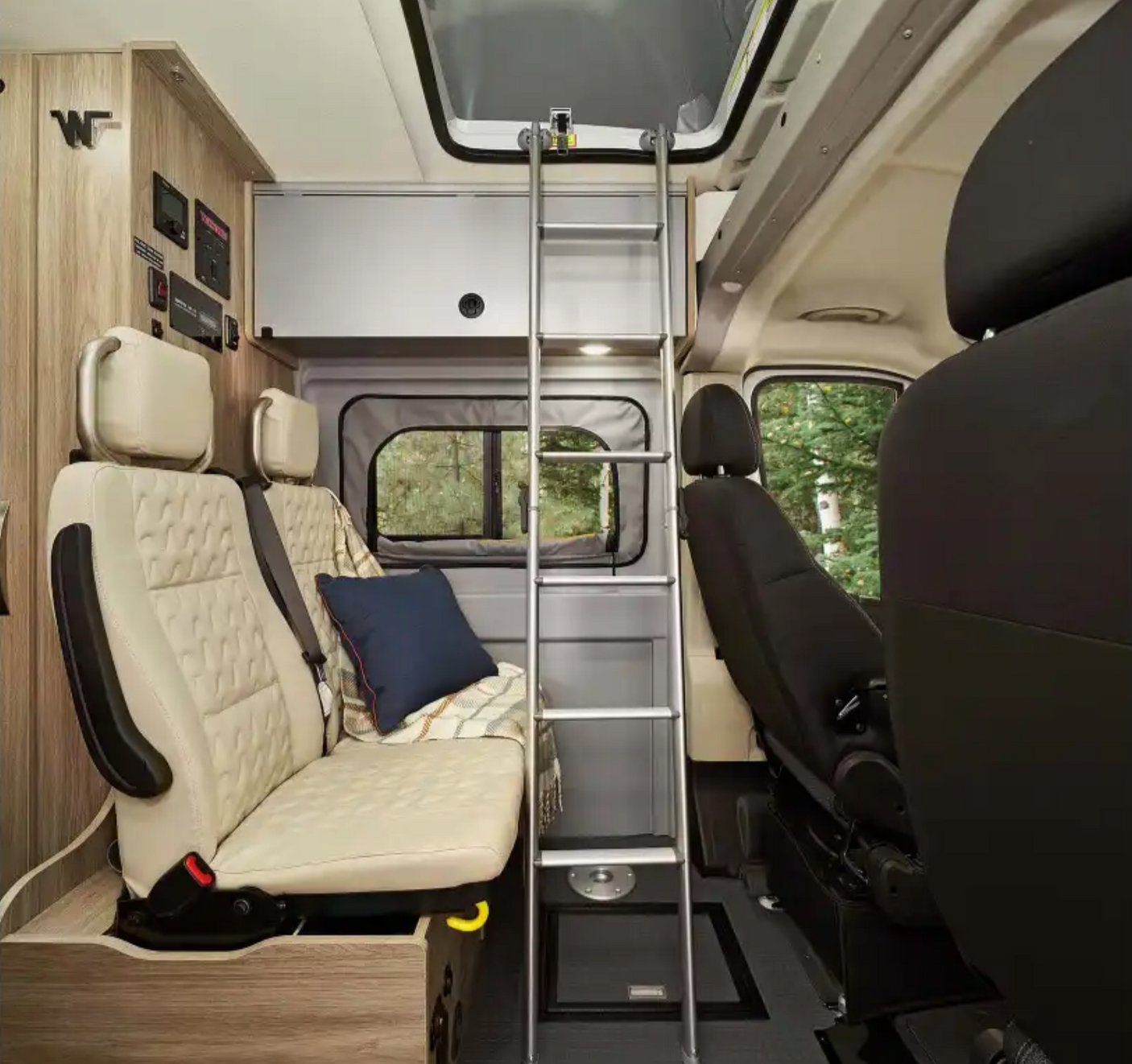 Interior of an **rv rental** showing versatile seating that converts to a bed, a ladder to an upper bunk, and control panels.