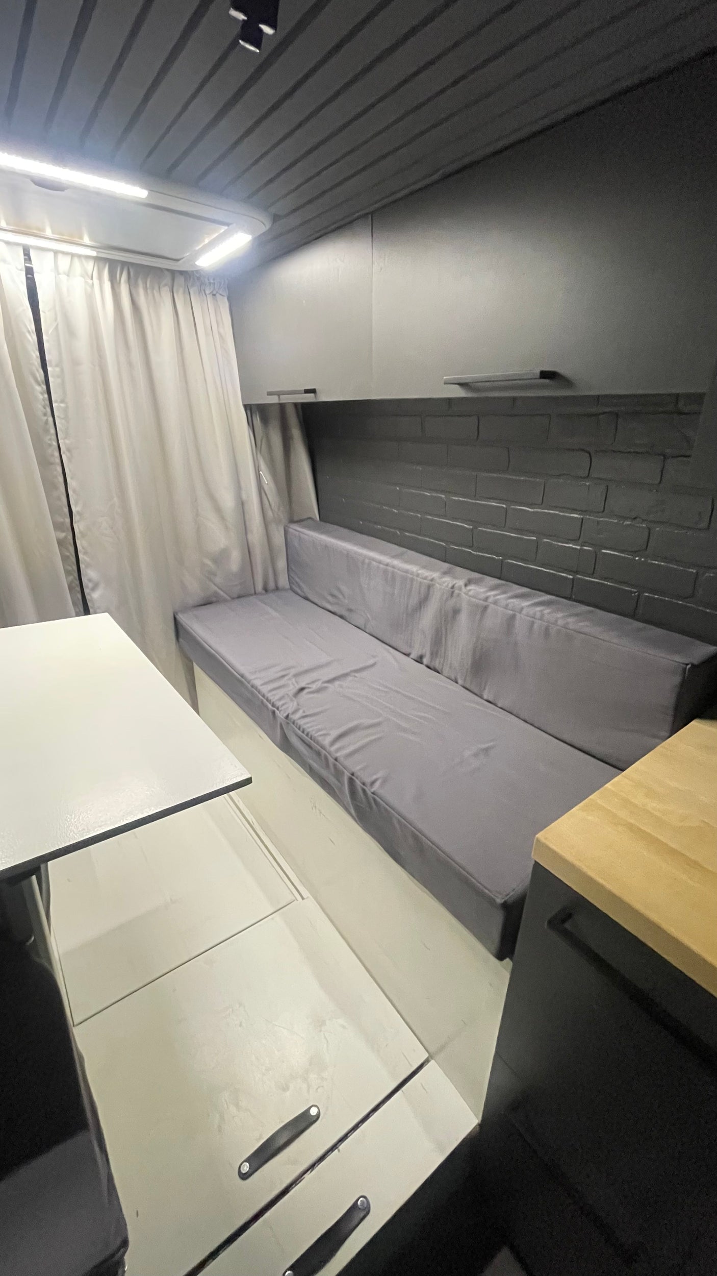 Modern RV rental interior: cozy seating, light wood & gray tones, smart storage.