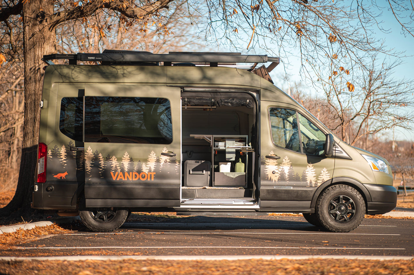 an ideal rv rental for your next adventure. Features tree graphics & roof rack.|Side profile of a green VANDOIT camper van RV rental