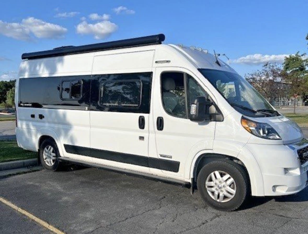 White high-roof camper van, featuring large side windows and an awning. Ideal for your next rv rental adventure.