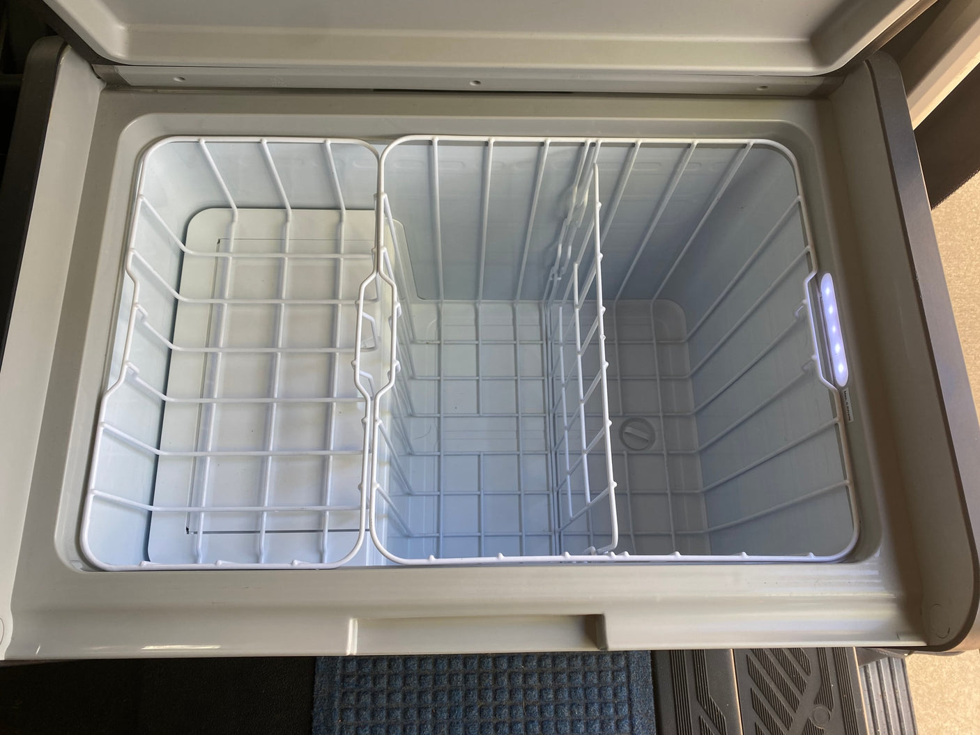 RV rental essential: Open portable fridge/freezer with internal baskets, ideal for travel cooler needs.