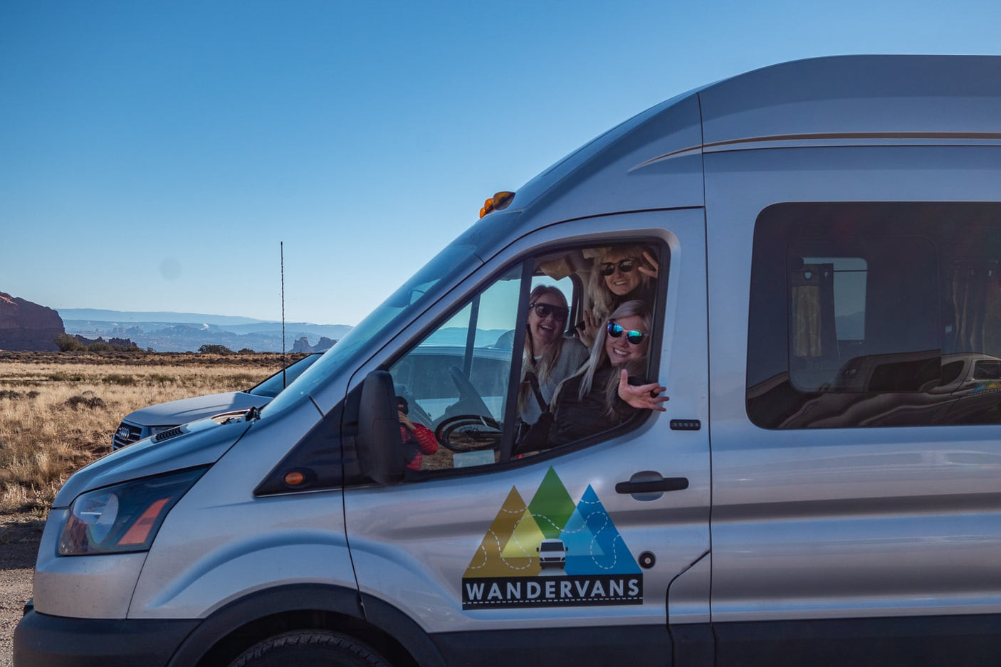 Smiling friends on a scenic outdoor RV rental adventure in their Wandervans van.