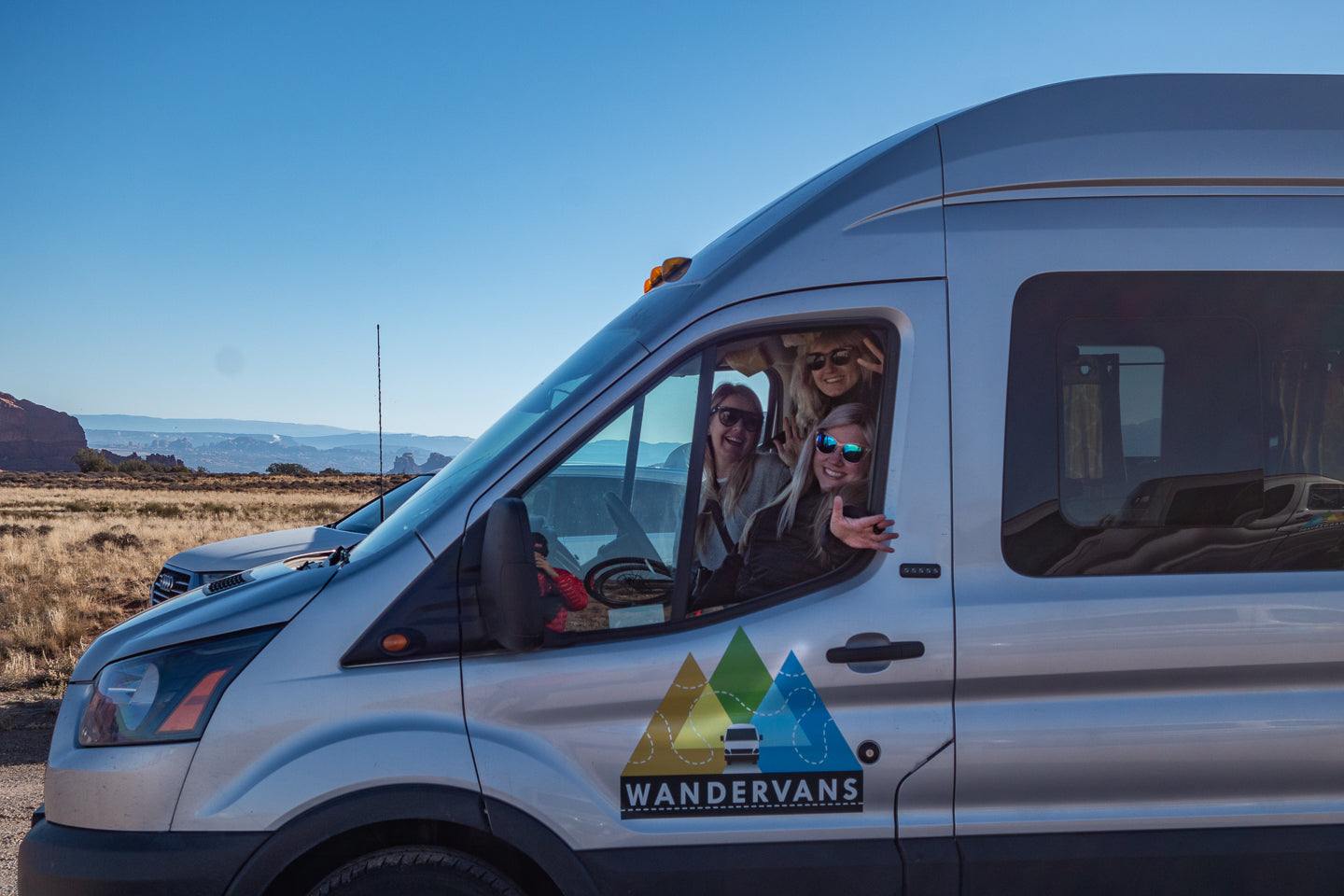 Smiling friends on a scenic outdoor RV rental adventure in their Wandervans van.