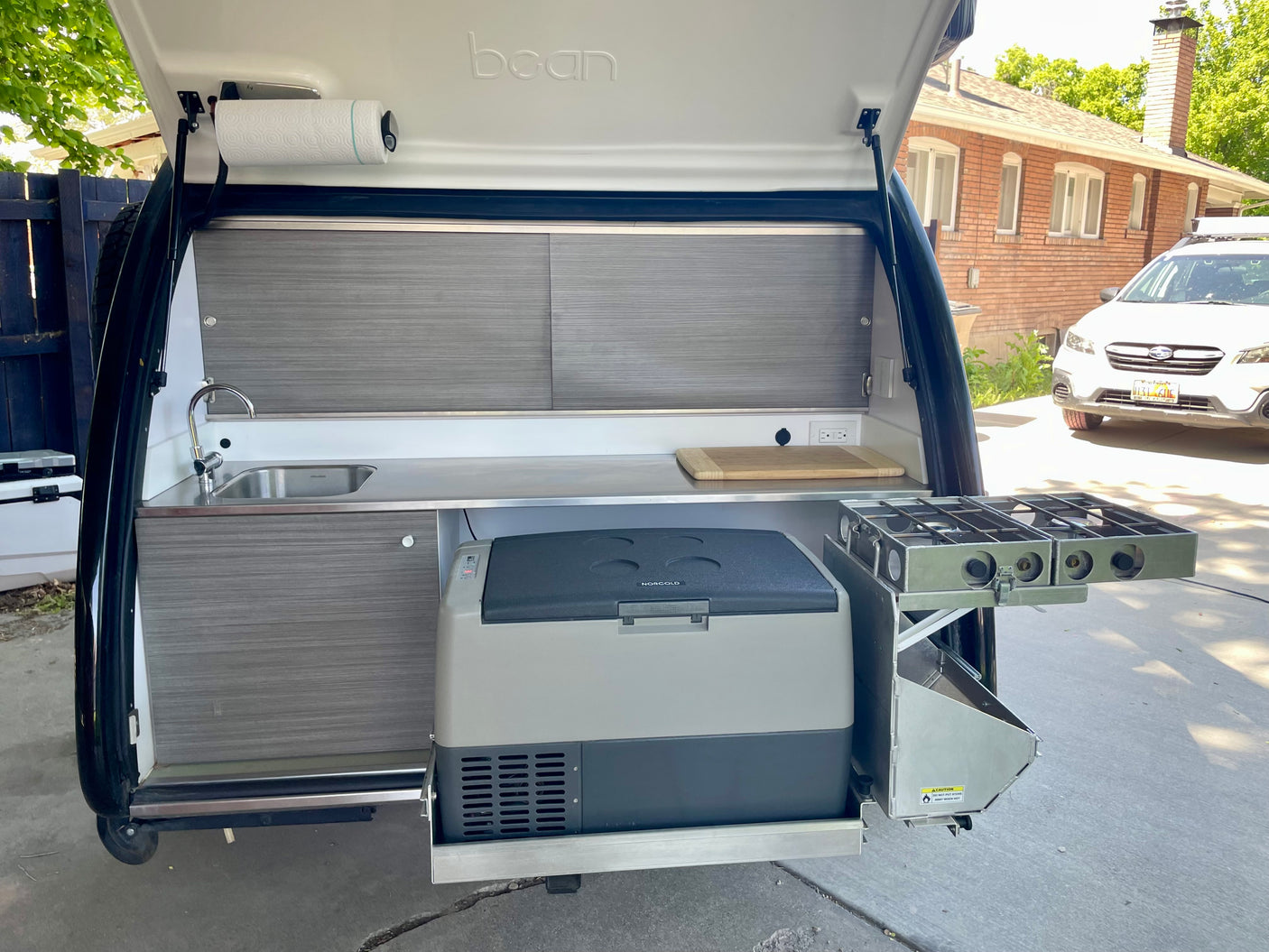 Explore this RV rental's compact rear kitchen: sink, stovetop, and fridge. Perfect for road trips!