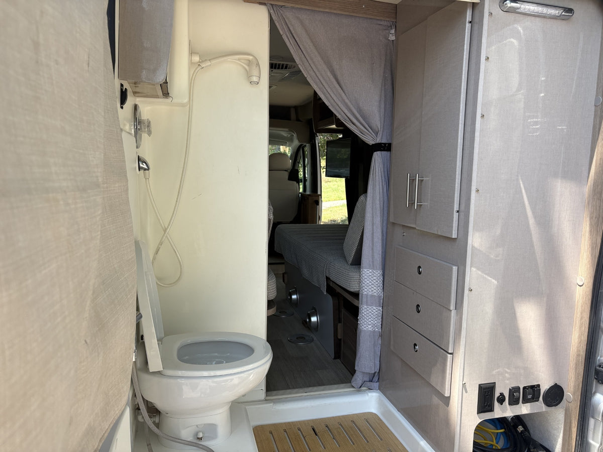 An rv rental's integrated bathroom features a toilet, shower, and cabinetry, offering a glimpse into the sleeping area. — photo 10