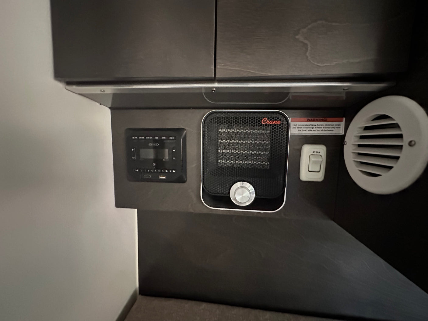 RV rental interior: integrated heater, AC fan switch, and multimedia panel with a safety warning. For comfort & control.