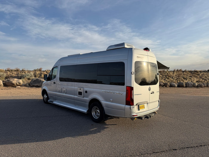 Silver Pleasure Way Sprinter RV rental camper van parked in a sunny, arid landscape with an extended awning.