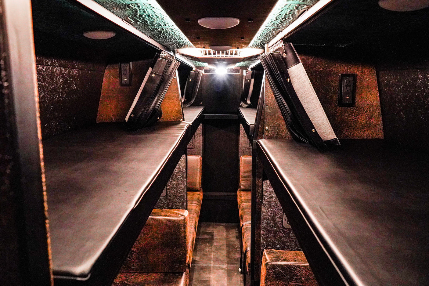 Cozy RV rental interior with multiple sleeping berths, textured walls, and charging outlets for comfort.