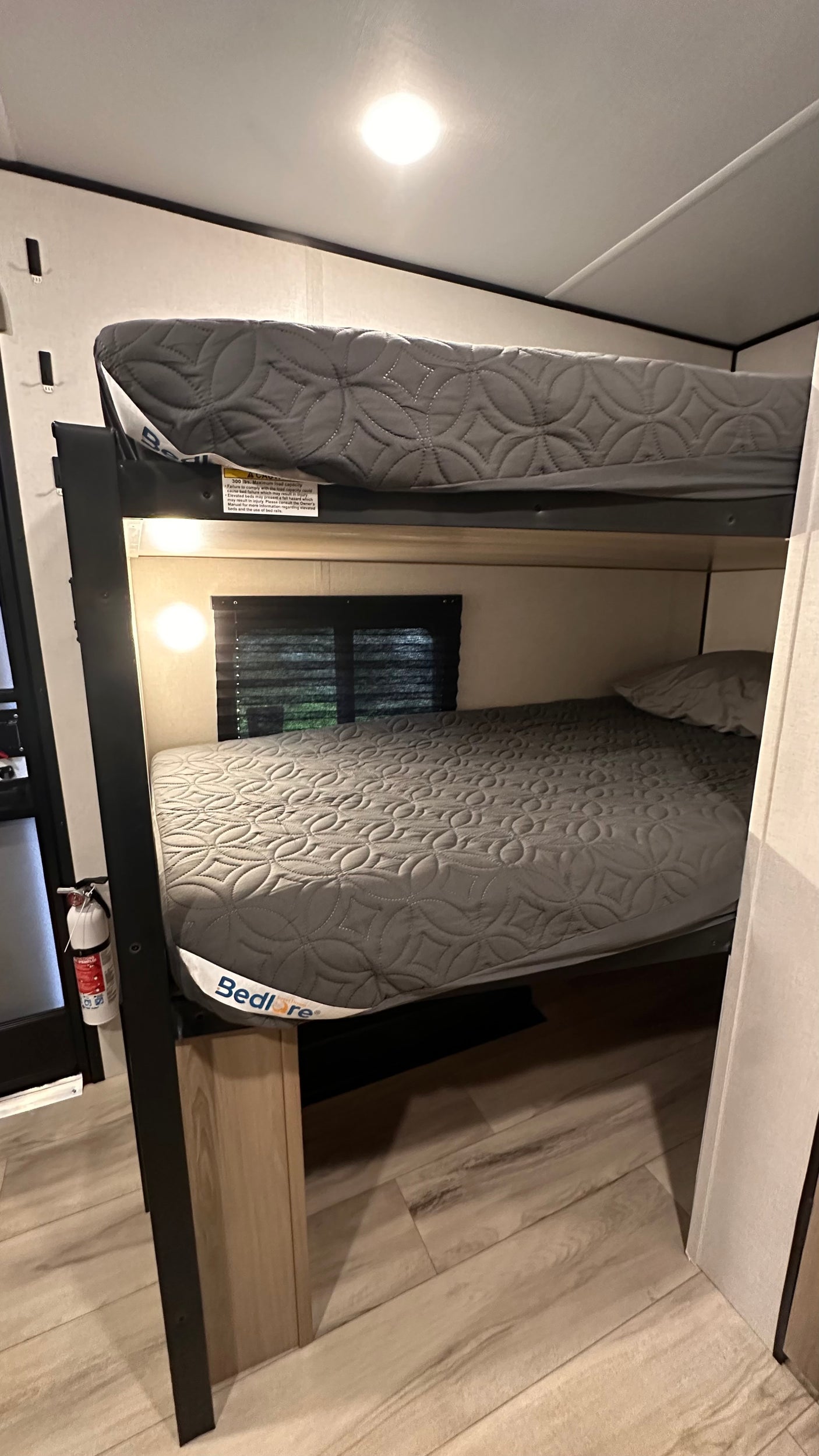 RV rental interior shows bunk beds with mattresses. A warning label on the upper bunk states 300 lbs max capacity.