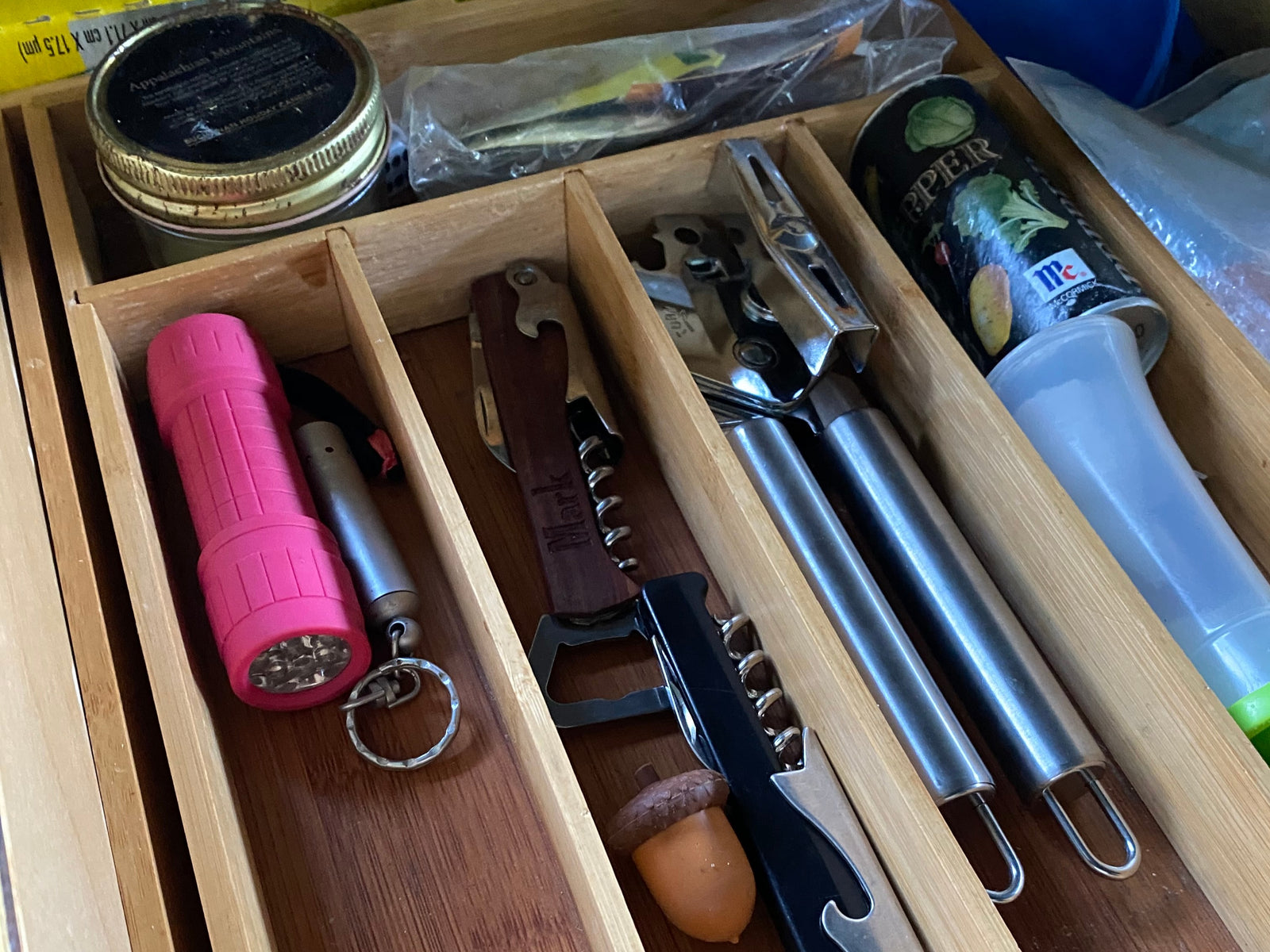 This RV rental's kitchen drawer organizer features a pink flashlight, corkscrews, spices, and cooking utensils, neatly stored.