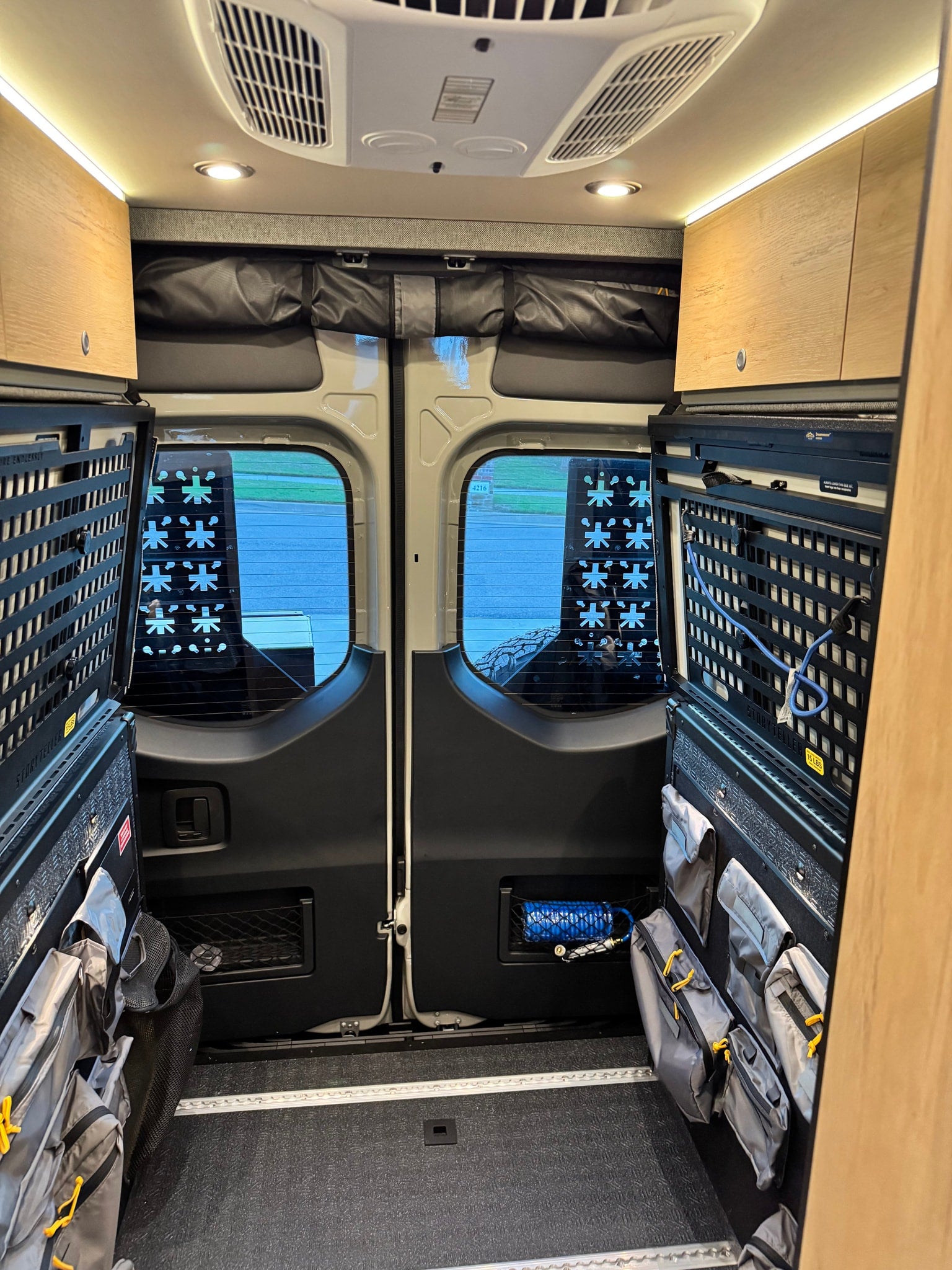 Inside this rv rental: well-equipped camper van interior features modular storage, rear doors, and ceiling lights for adventure.