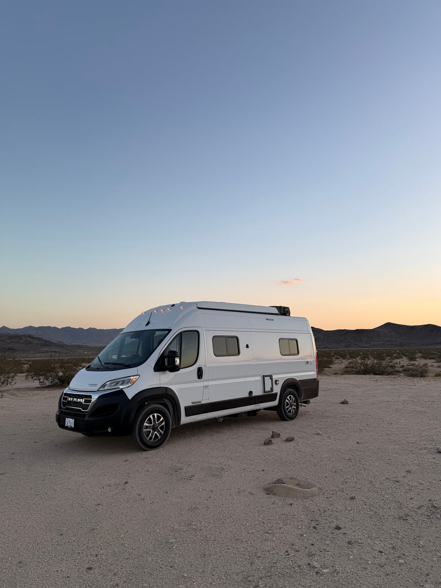 chairs set for stargazing.|Experience starry nights in an RV rental! A camper van with its pop-top extended is parked under a clear