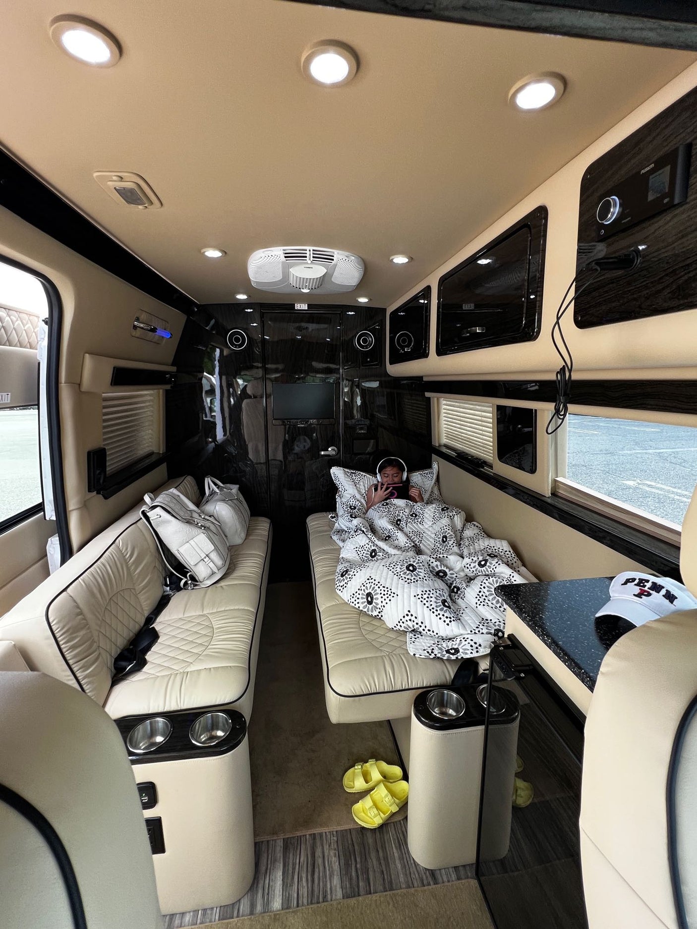 Plush RV rental interior: A person relaxes on a cozy bed inside a luxury van, perfect for comfortable travel.