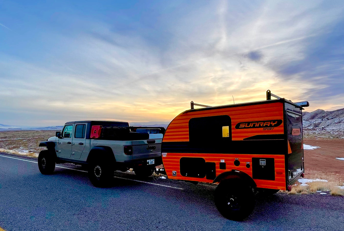 Jeep Gladiator towing a Sunray Sport teardrop camper for a scenic rv rental adventure at sunset in a vast landscape.