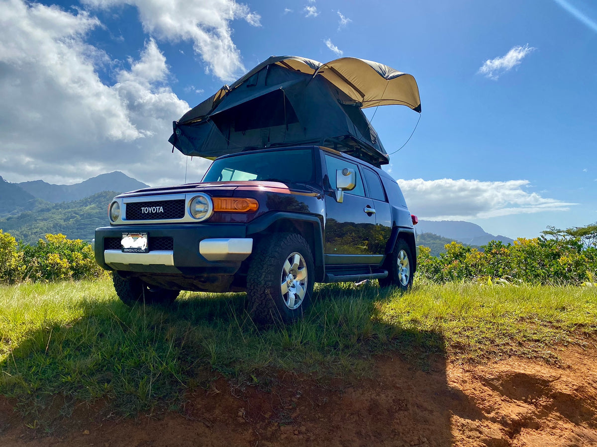 Toyota FJ Cruiser with rooftop tent, parked on a grassy hill overlooking Hawaii's mountains. Perfect RV rental for adventure. — photo 9