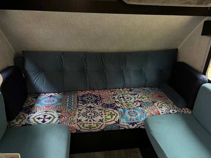 ideal for camping.|Cozy RV rental interior featuring a blue tufted sofa bed and colorful patterned bedding