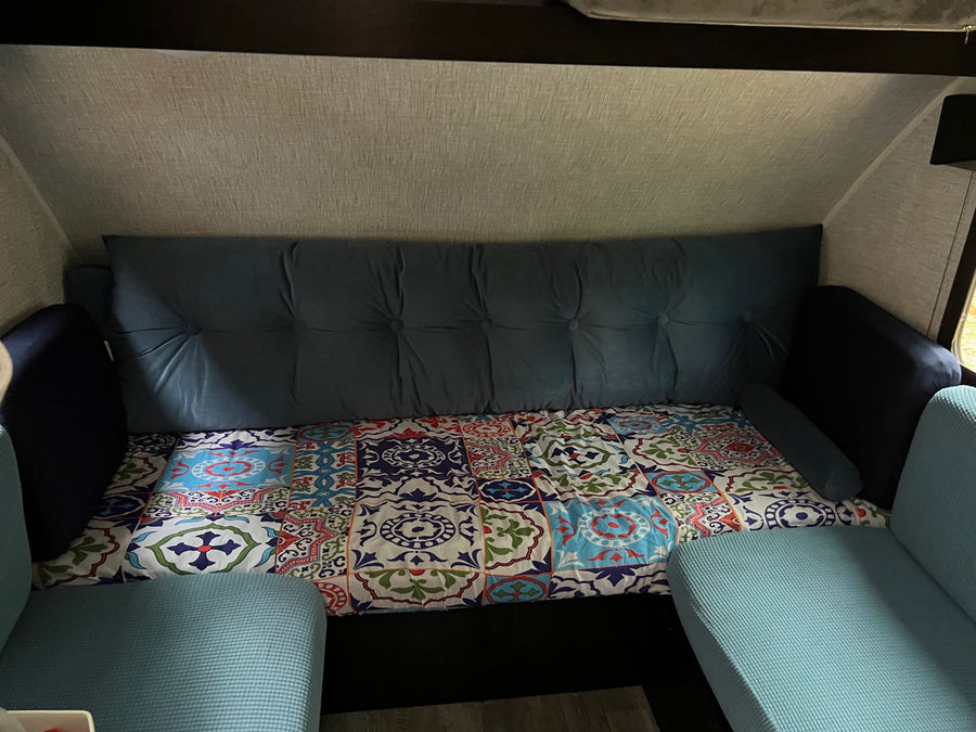 ideal for camping.|Cozy RV rental interior featuring a blue tufted sofa bed and colorful patterned bedding