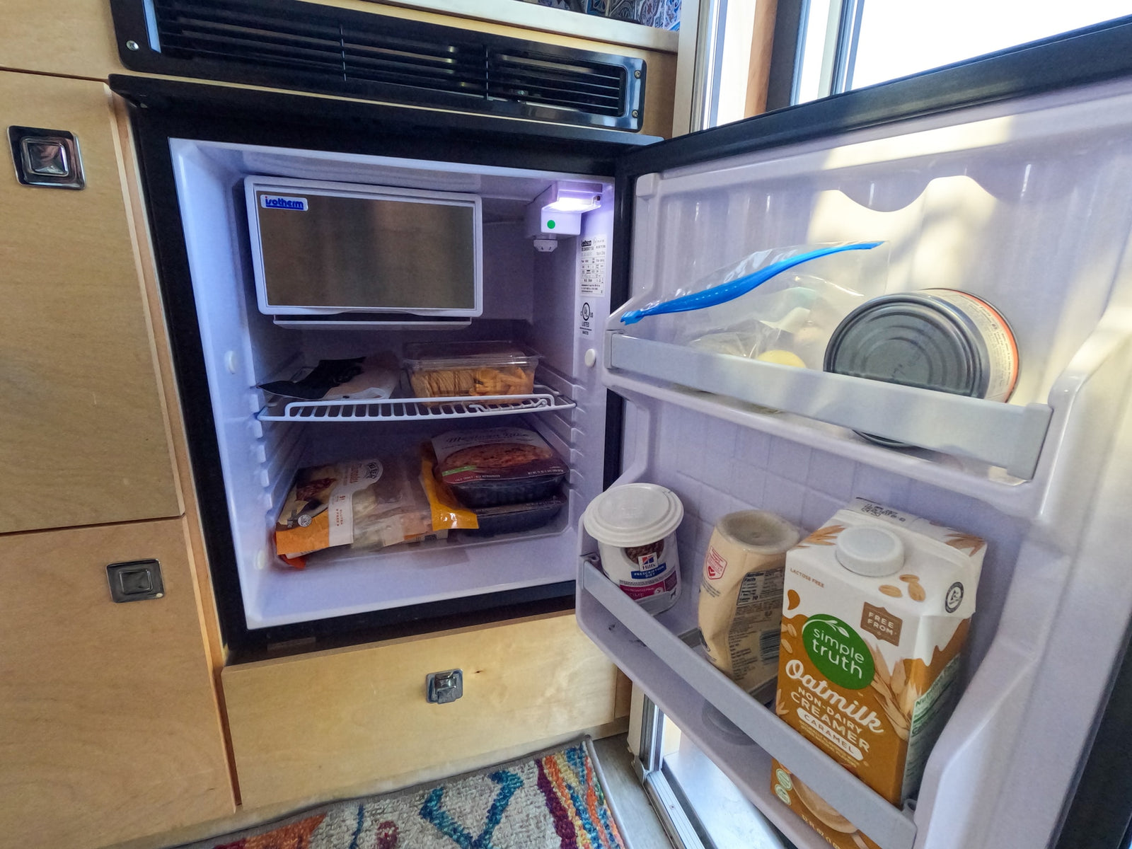Inside an RV rental's Isotherm fridge, packed with oat milk, food, and a small freezer. Ready for road trip meals.