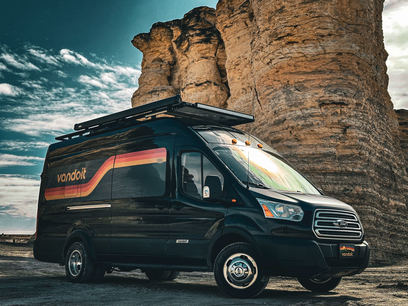 Customized black Ford Transit Vandoit rv rental parked among towering rock formations