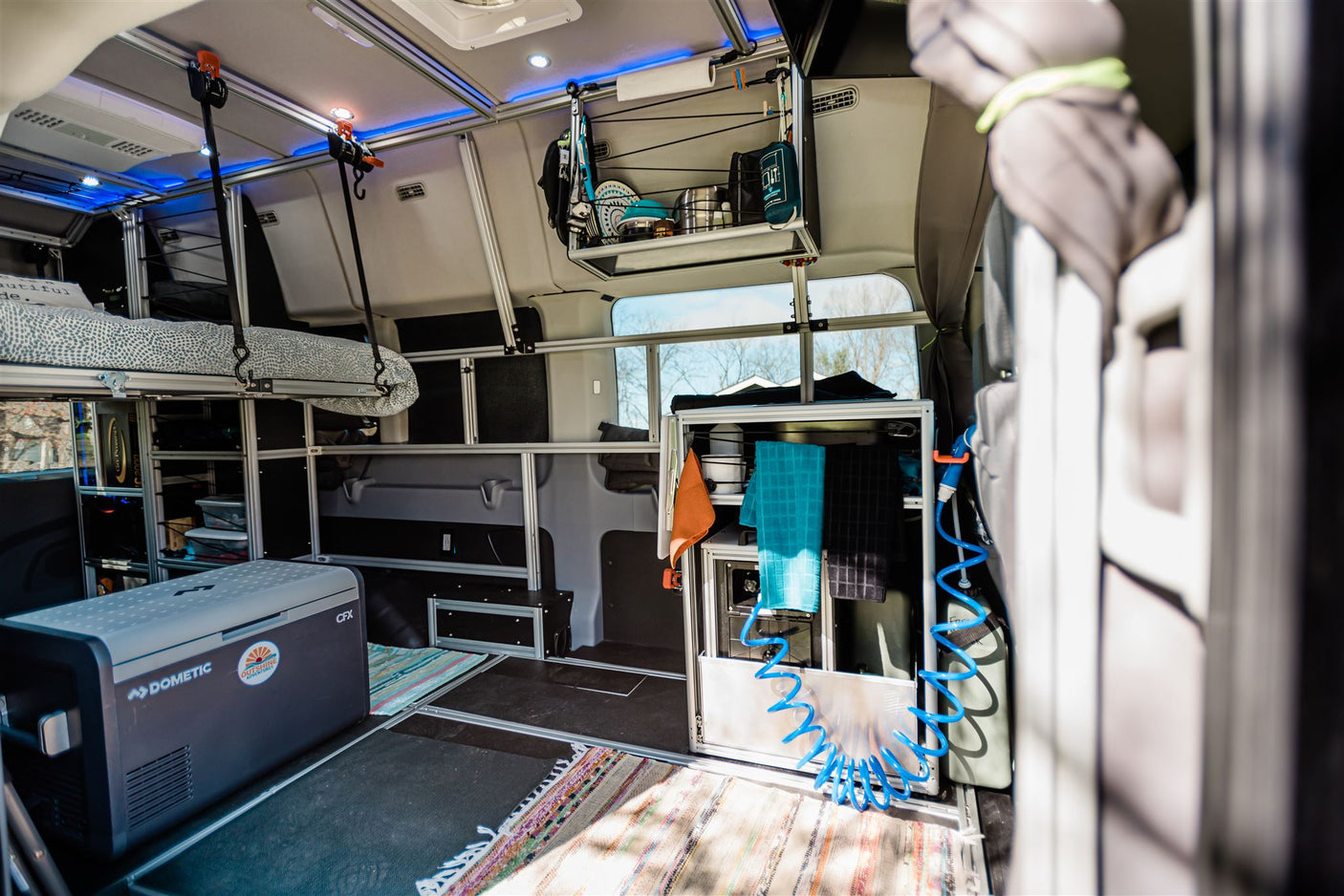 and abundant storage racks and shelves.|Spacious rv rental camper van interior with an elevated bed