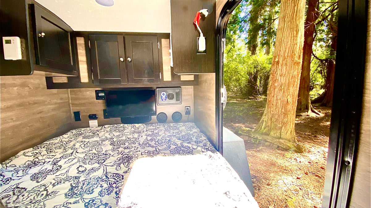 RV rental bedroom with TV, cabinets, & open door showing a sunny forest view. Ideal for travel & camping. — photo 10