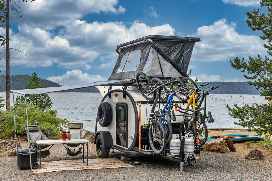 Lakeside RV rental: A teardrop camper with bikes, rooftop tent, and awning for an ultimate outdoor adventure.