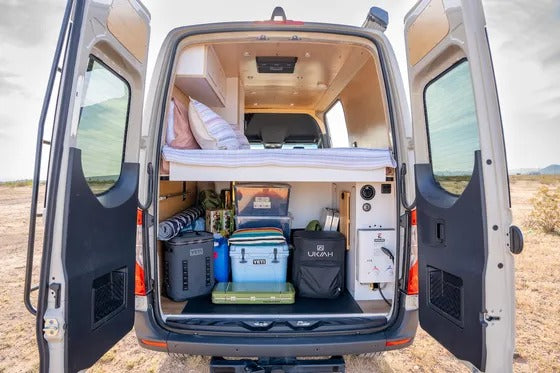 Spacious **RV rental**: organized camper van interior with bed, ample storage, and gear for outdoor adventures.
