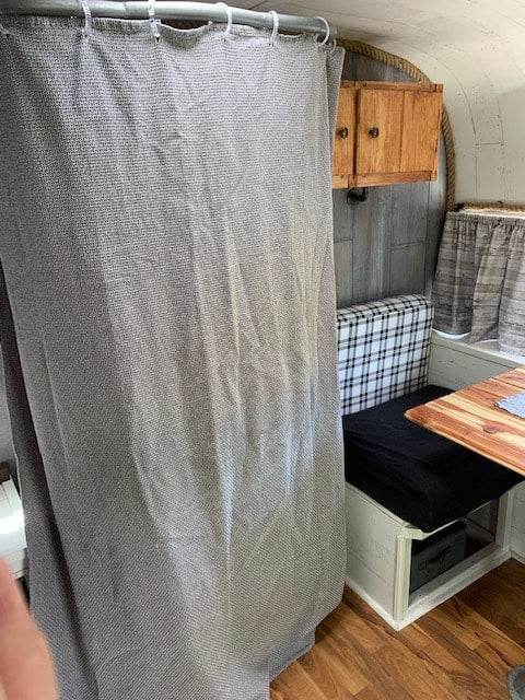RV rental: Compact interior with a grey bed, wooden table, and clever storage. Ideal for travel comfort.
