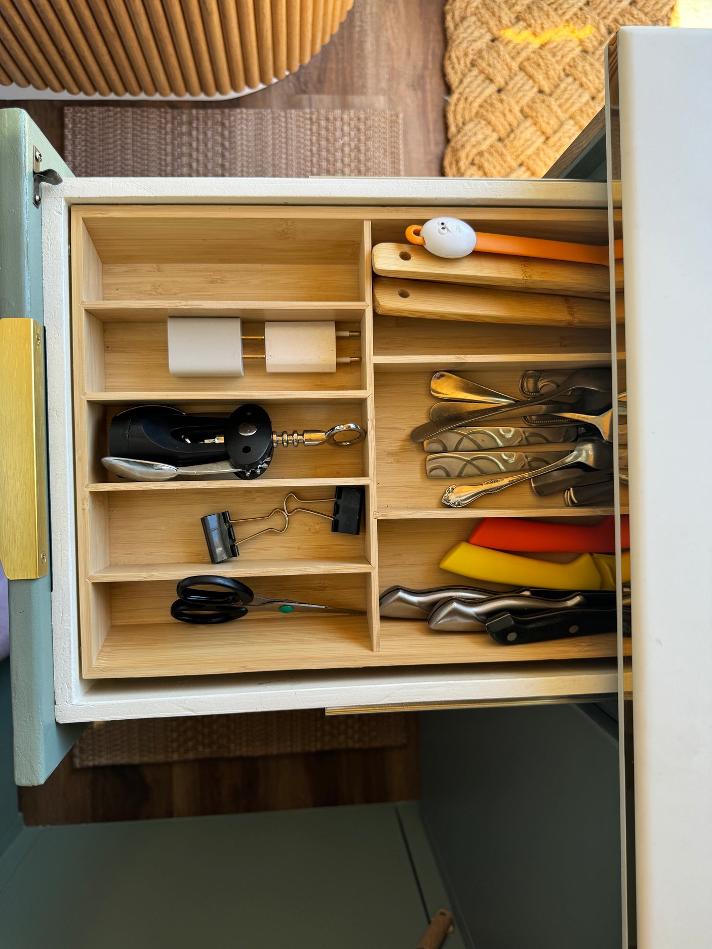 Organized kitchen drawer in an RV rental, filled with utensils, chargers, and knives, optimizing compact space.