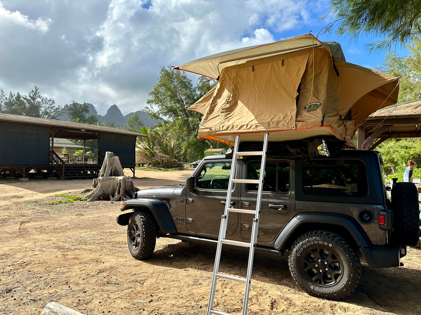 Overlanding Jeep with a Delka rooftop tent, resembling an RV rental, ready for camping by mountains. — photo 1