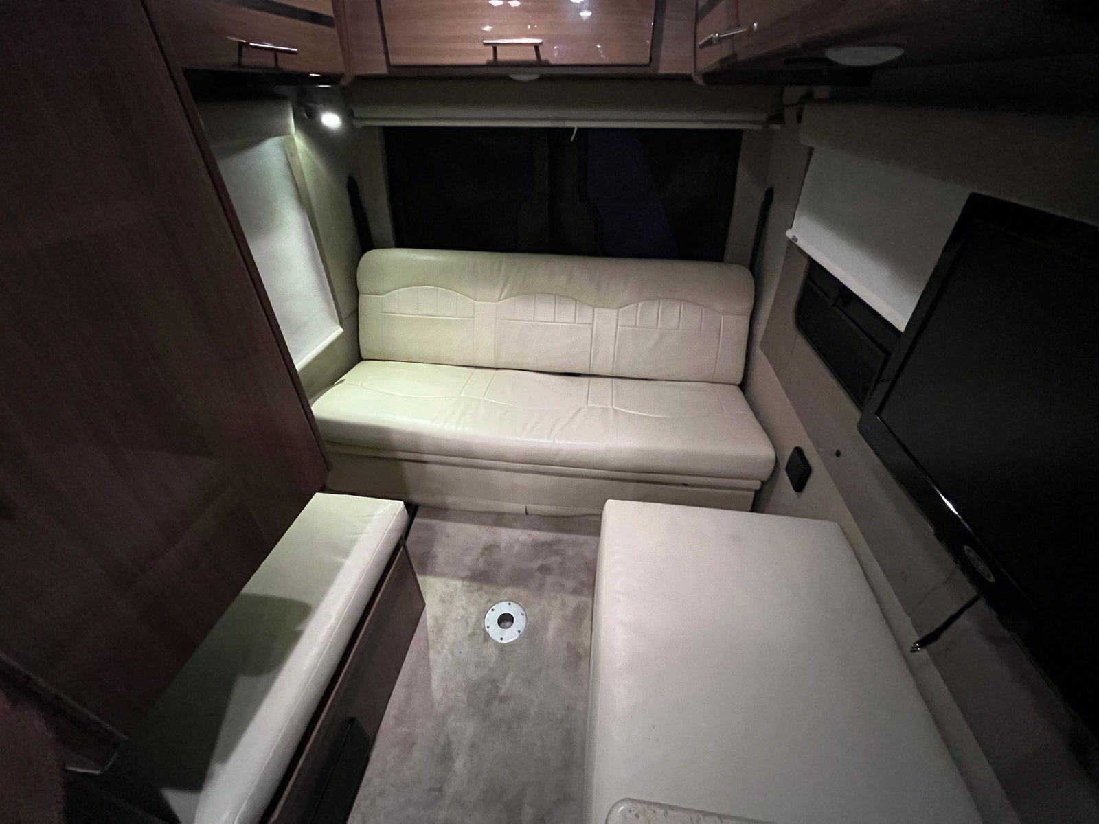 and small sink for efficient space utilization.|RV rental interior: A cozy living area featuring a long beige sofa at the back