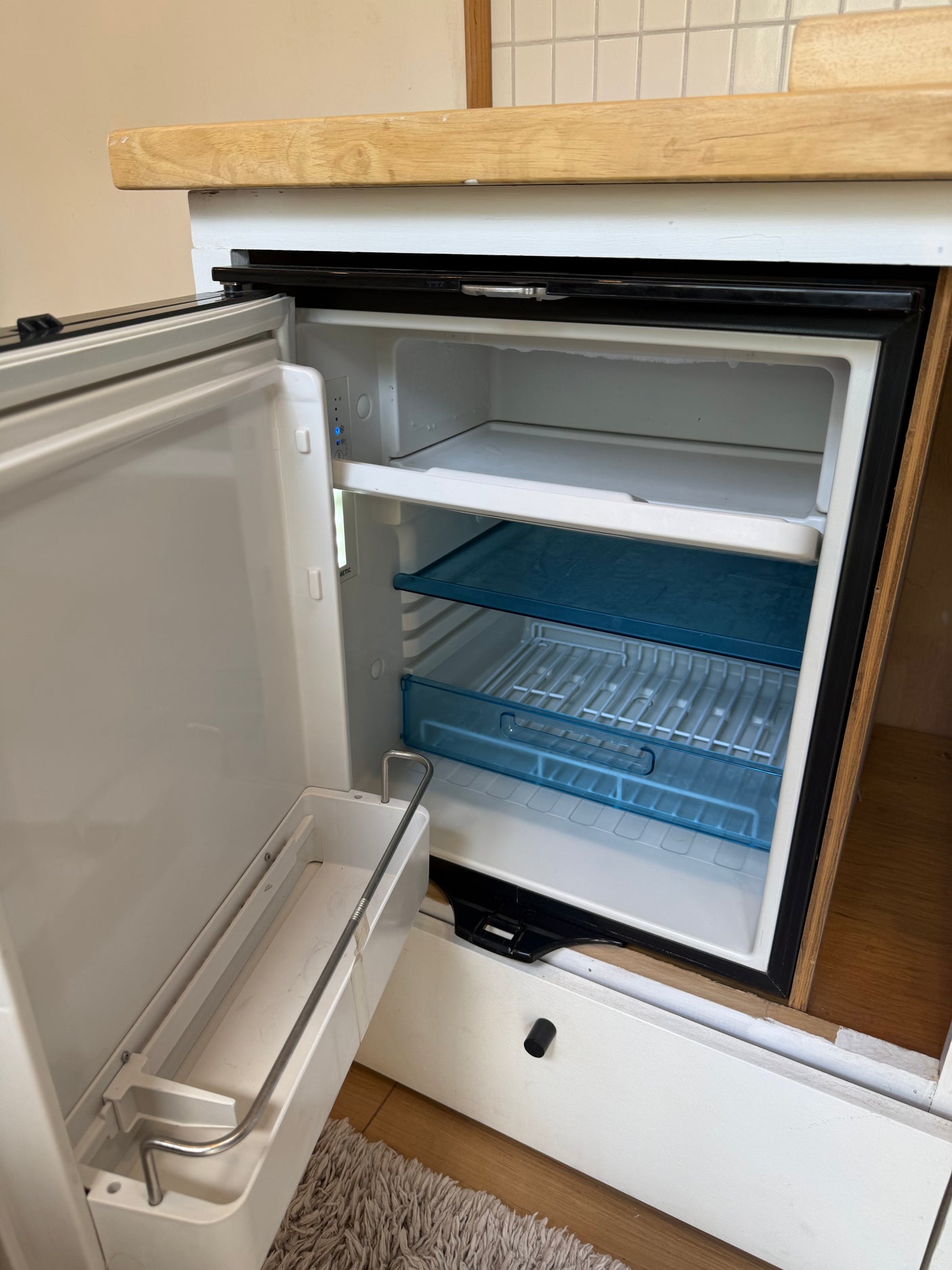 RV rental: Open mini-fridge with freezer, shelves, and door storage, ready for use in a compact kitchen setting.