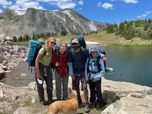 Family and dog on a backpacking trip in mountains by a serene lake. Amazing outdoor adventure after their rv rental journey.