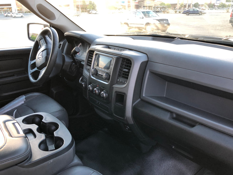 Driver's view from an RV rental truck: black dashboard, steering wheel, and bright parking lot visible through windshield.