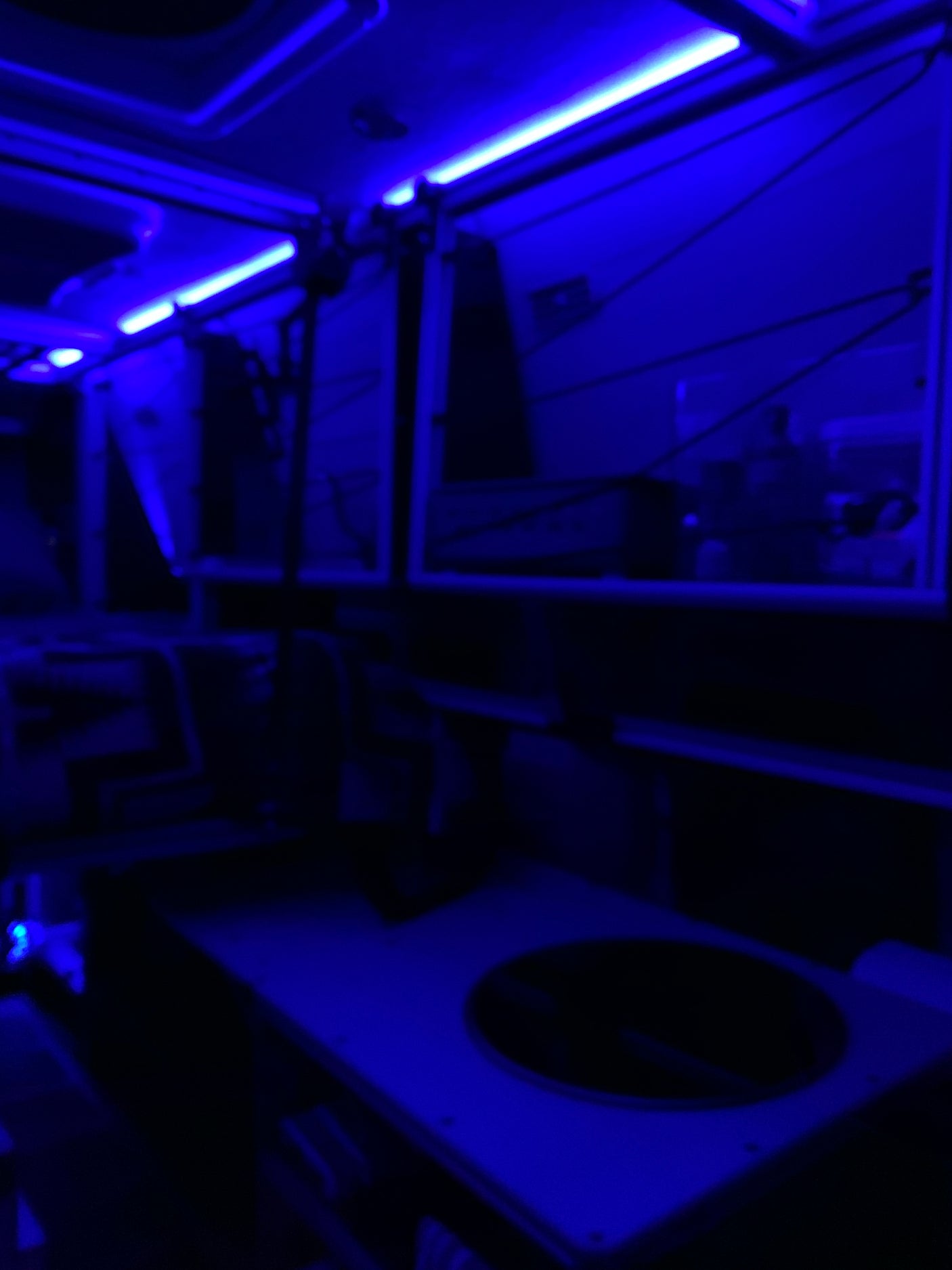 An RV rental's modern interior glows with blue light. The cabin is dark, accented by bright strips for a unique travel experience.