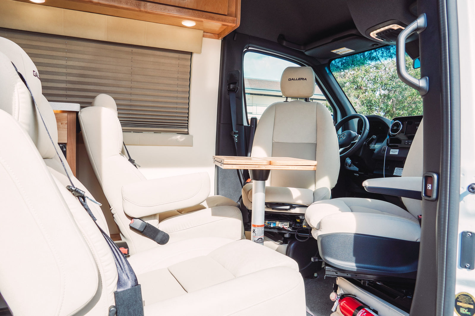 Experience comfort in this luxury RV rental. Features plush cream seating, a portable table, and a clean, inviting interior.