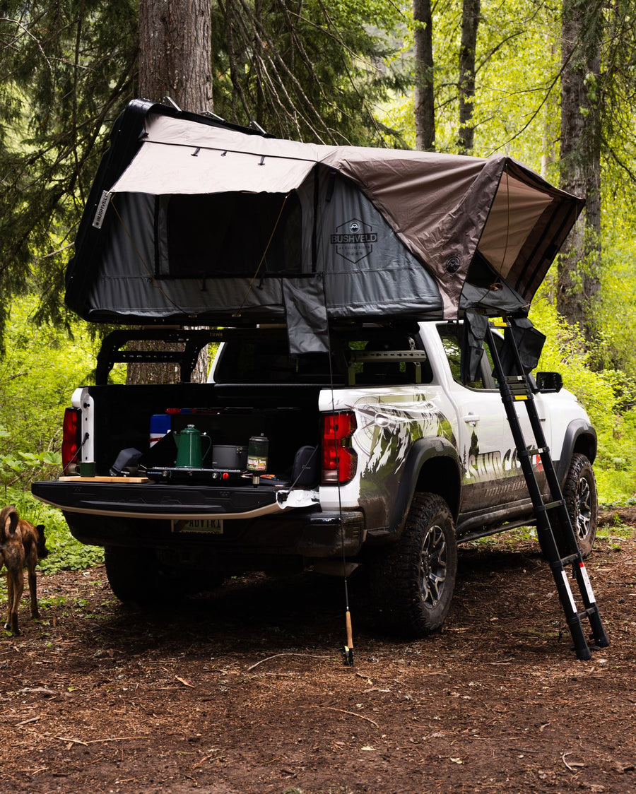 perfect for overland adventure. Consider this alternative to RV rental.|Camping truck with rooftop tent and gear in forest campsite