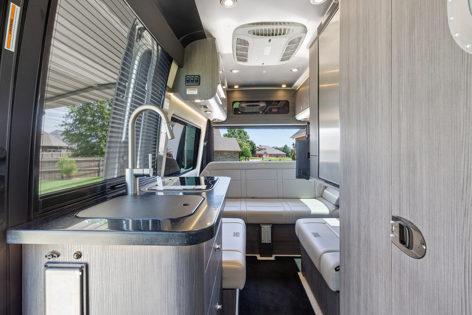 ready for RV rental. Side door open reveals modern interior.|Rear view of a silver RV rental camper van