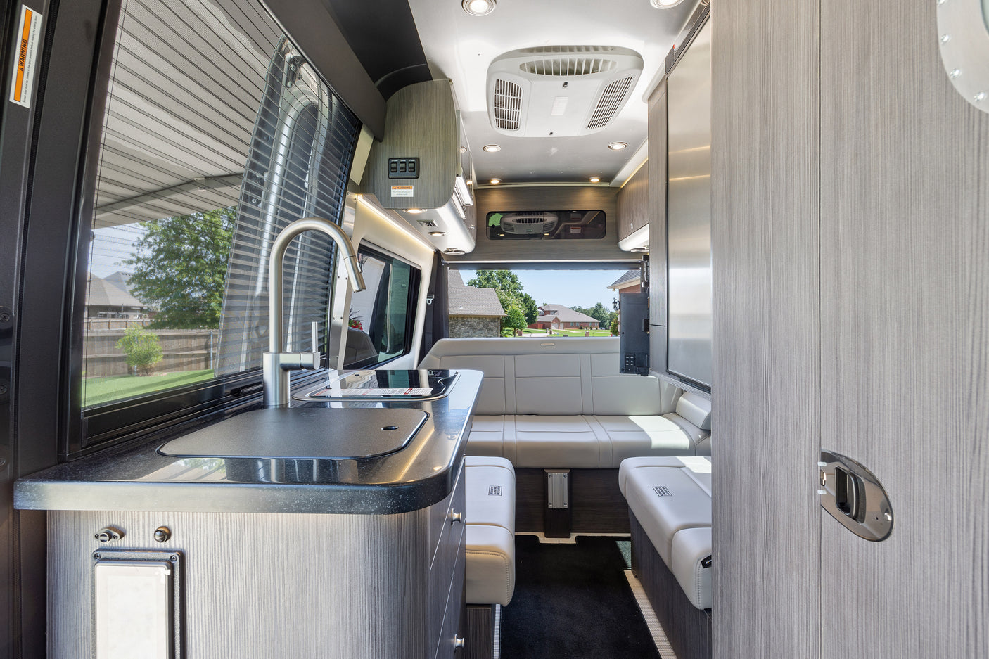 ready for RV rental. Side door open reveals modern interior.|Rear view of a silver RV rental camper van