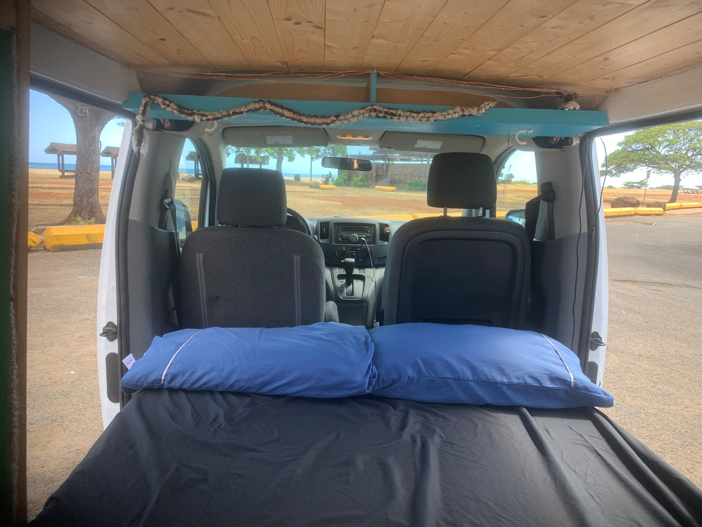 RV rental ready for adventure: Van interior with bed, facing beach views. Perfect for car camping and van life.